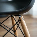 Black dining chair side profile showing wooden dowel legs and UV-coated ABS shell